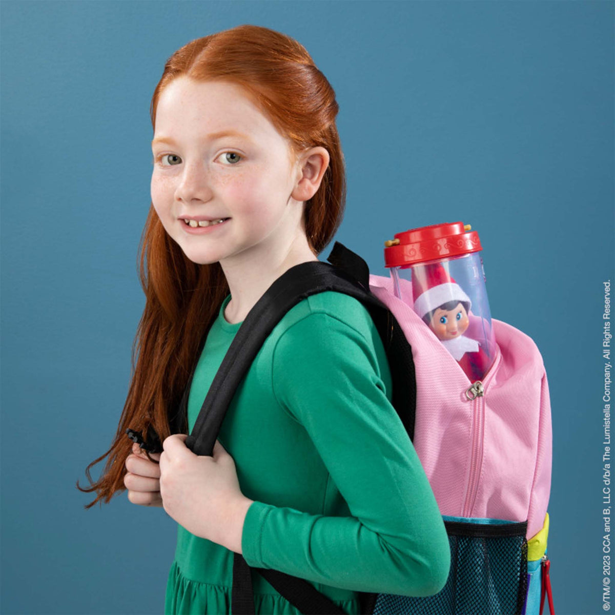 Girl with a pink backpack featuring a toy figure against a blue background