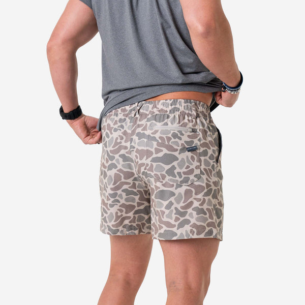Man wearing Burlebo Everyday Shorts in Classic Deer Camo and a grey t-shirt in front of a white background