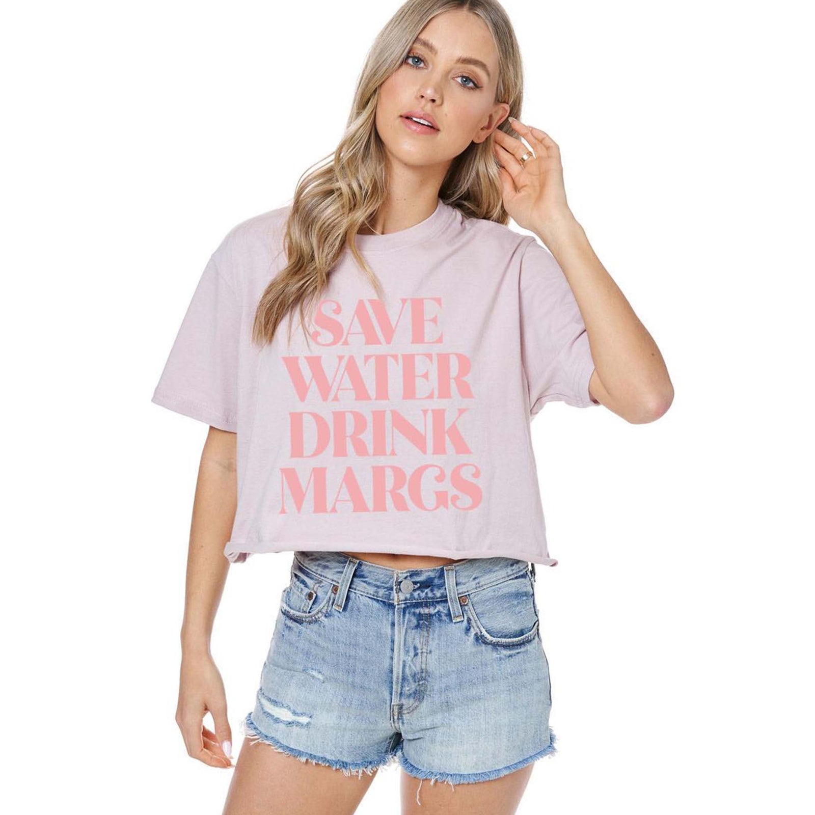 Save Water Drink Margs Crop Tee – front view of a woman wearing a rose crop t-shirt with bold pink text and denim shorts.