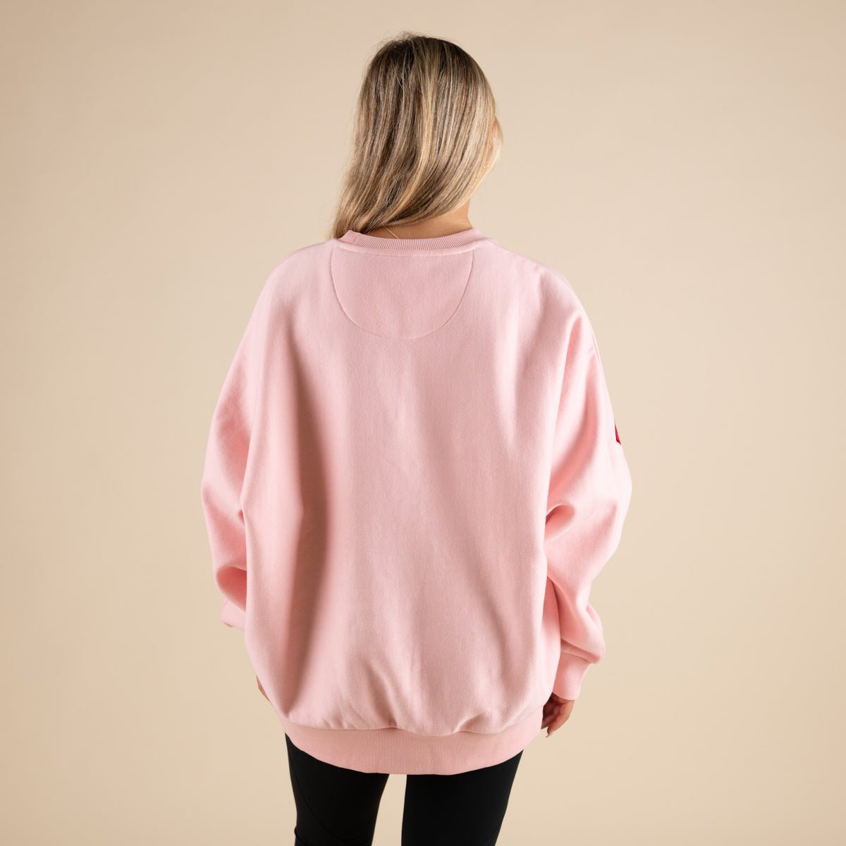 Person wearing a pink sweatshirt on a beige background