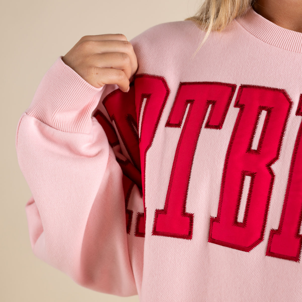 Pink sweater with red letters on a beige background