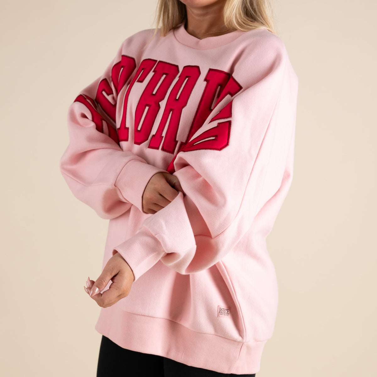 Person wearing a pink sweatshirt with red text on a beige background