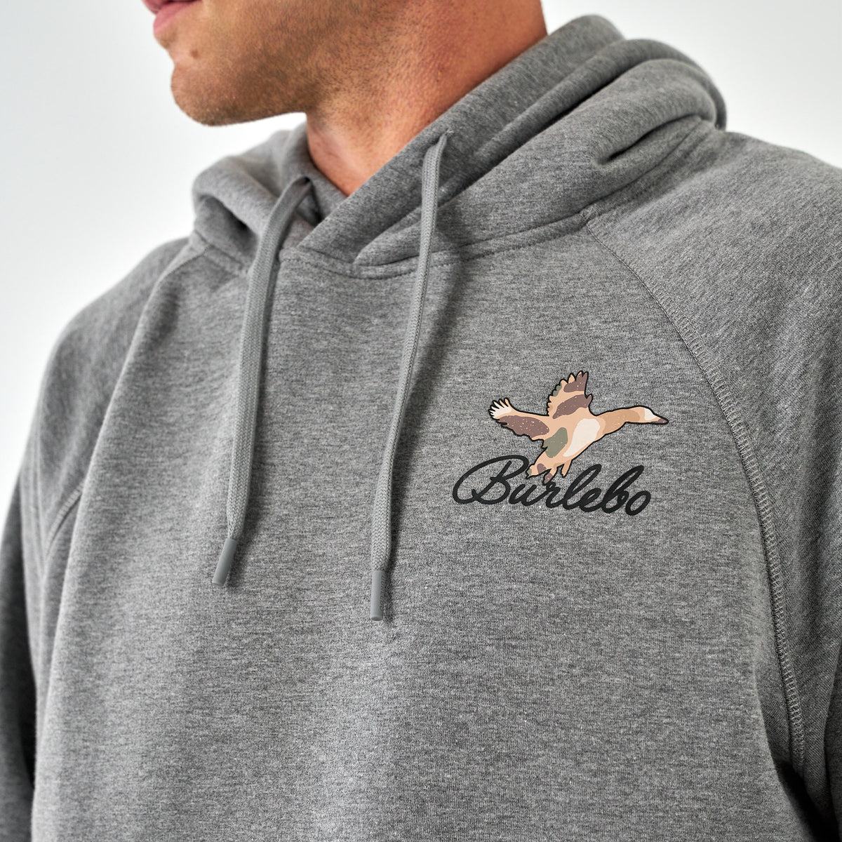 Close-up of Burlebo gray hoodie chest graphic featuring camo duck in flight with Burlebo script.