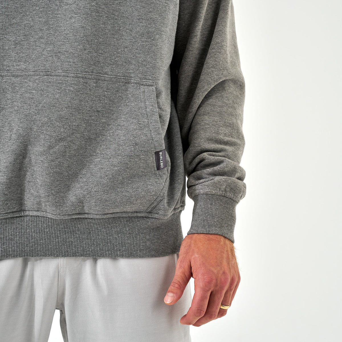 Close-up of Burlebo gray hoodie kangaroo pocket with small Burlebo fabric tag on the hem.