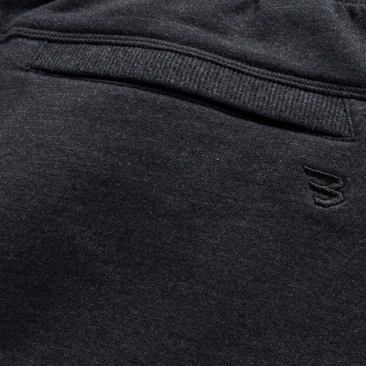 Close-up of back pocket on dark charcoal joggers with tonal embroidered Burlebo logo above the pocket seam.