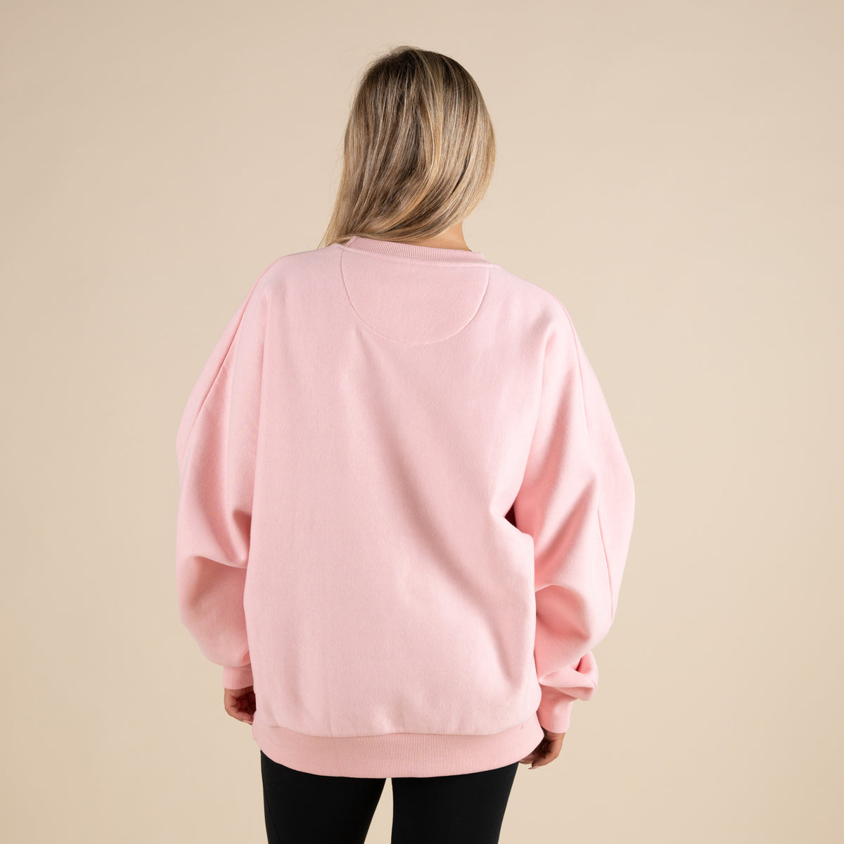Person wearing a pink sweatshirt on a beige background