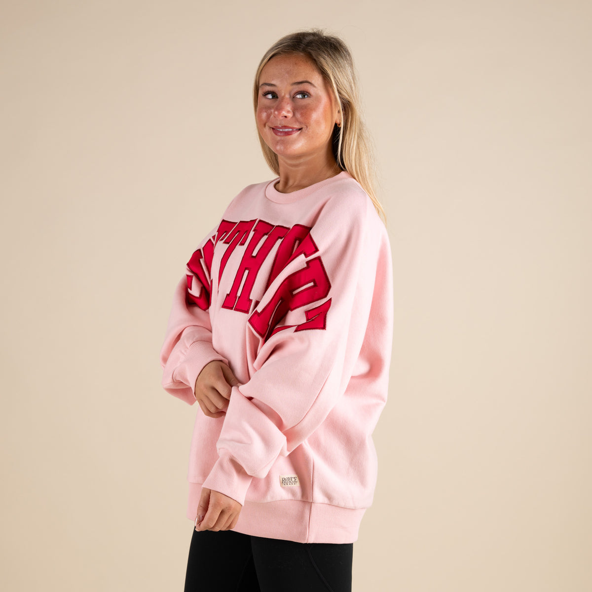 Person wearing a pink sweatshirt with red text on a beige background