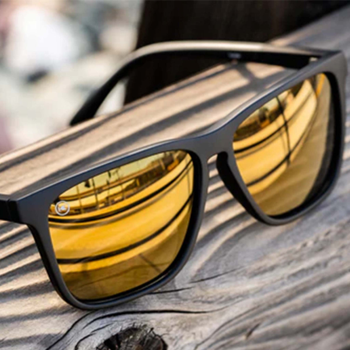 Sunglasses with gold reflective lenses on a wooden surface