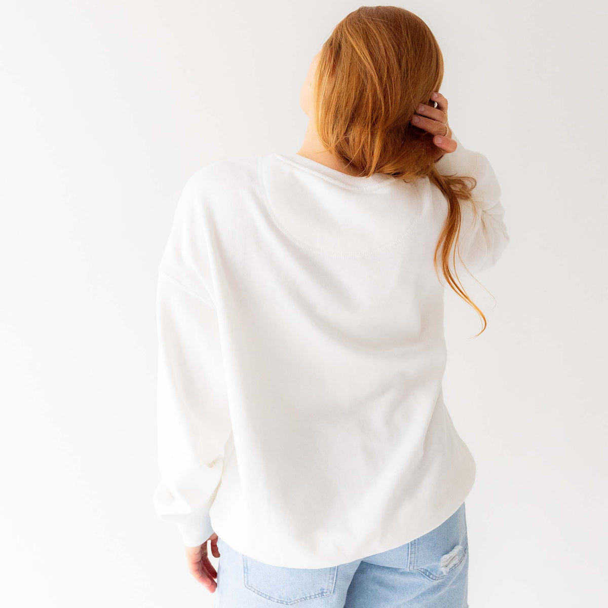 Back view of plain white crewneck sweatshirt with no graphics.