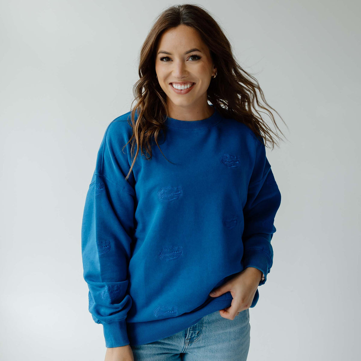 Front view of woman wearing royal blue crewneck sweatshirt with tonal embroidered Gators head logos and relaxed fit.