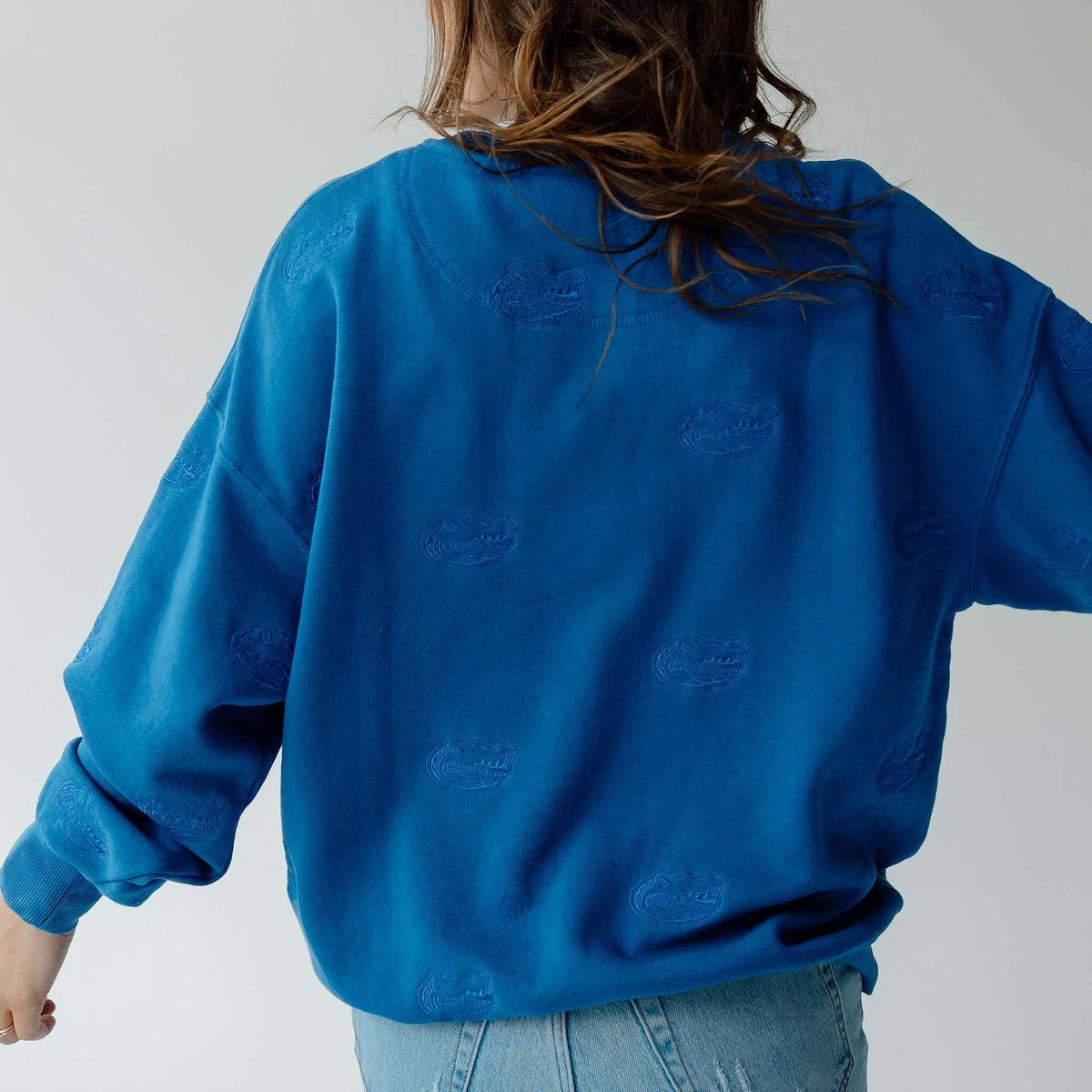 Back view of royal blue crewneck sweatshirt with allover tonal embroidered Florida Gators head logos.