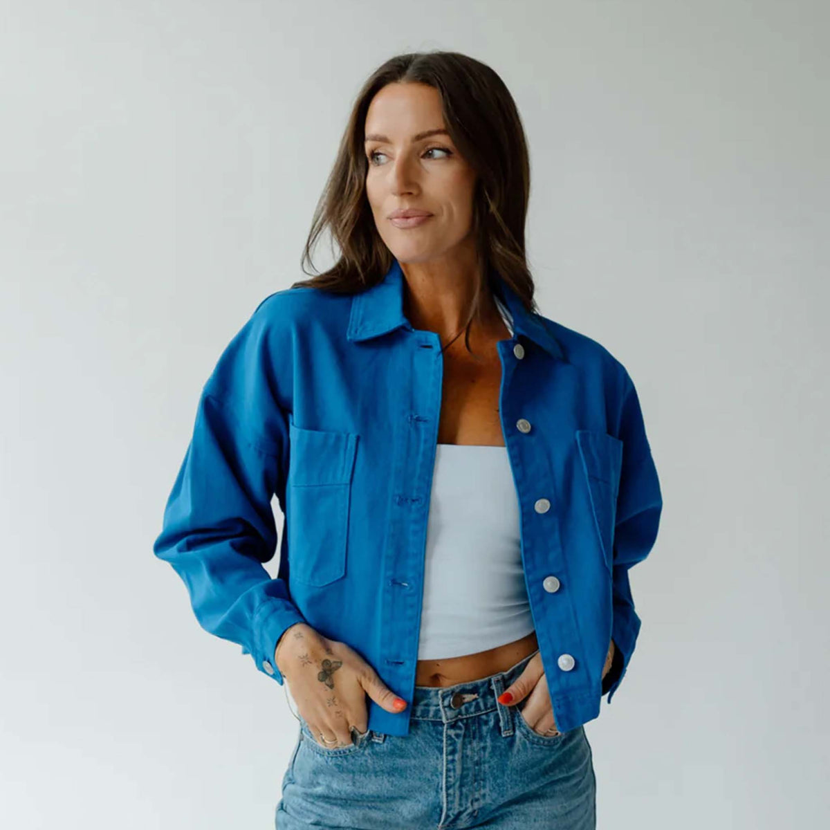Front view of woman wearing royal blue cropped canvas twill jacket with button-front closure and two chest pockets.