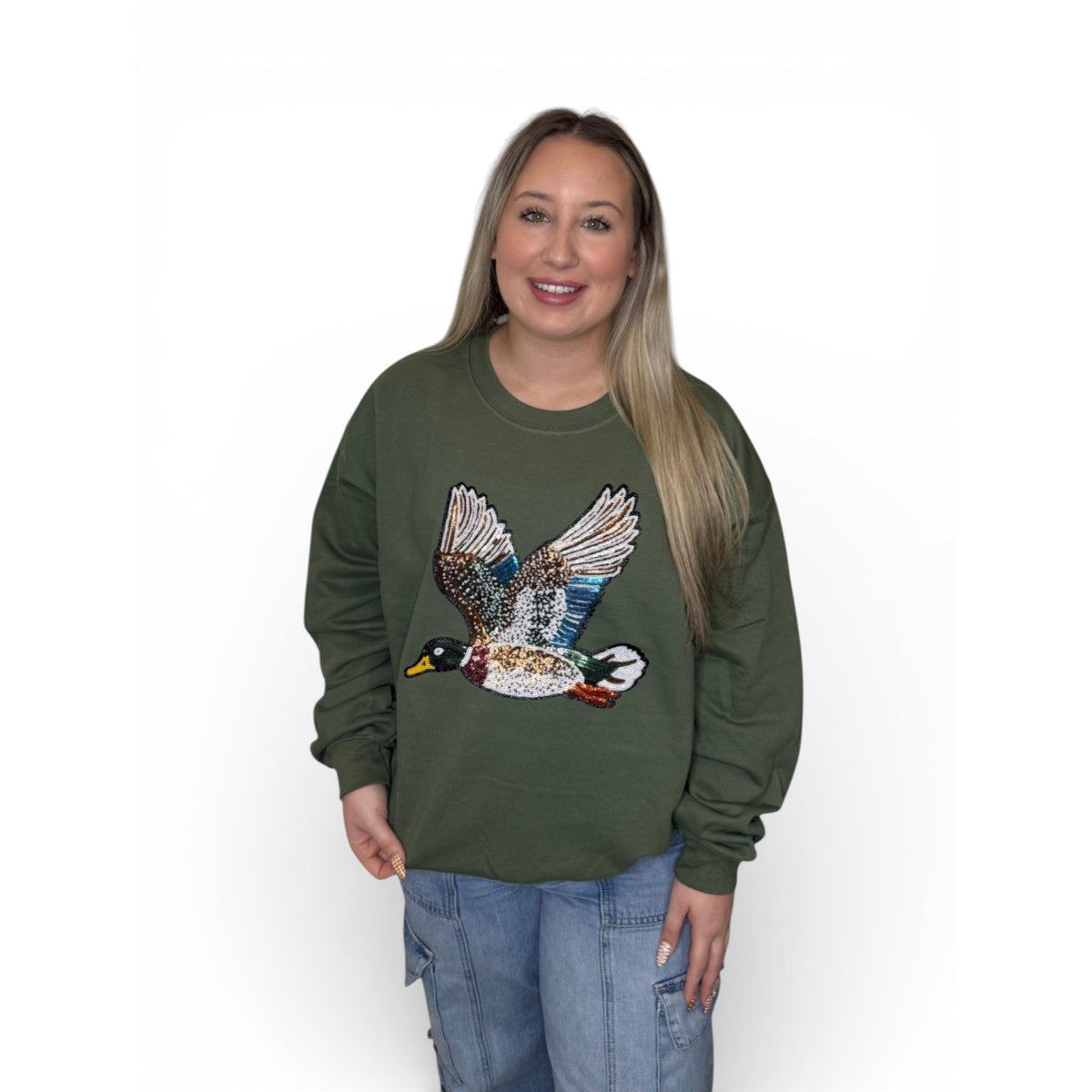 Woman wearing military green crewneck sweatshirt with large flying duck graphic on the front.