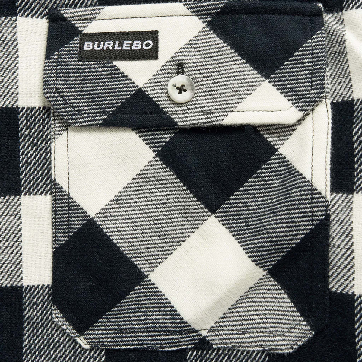 Close-up of a black and white checkered shirt with 'Burlebo' branding on a button.