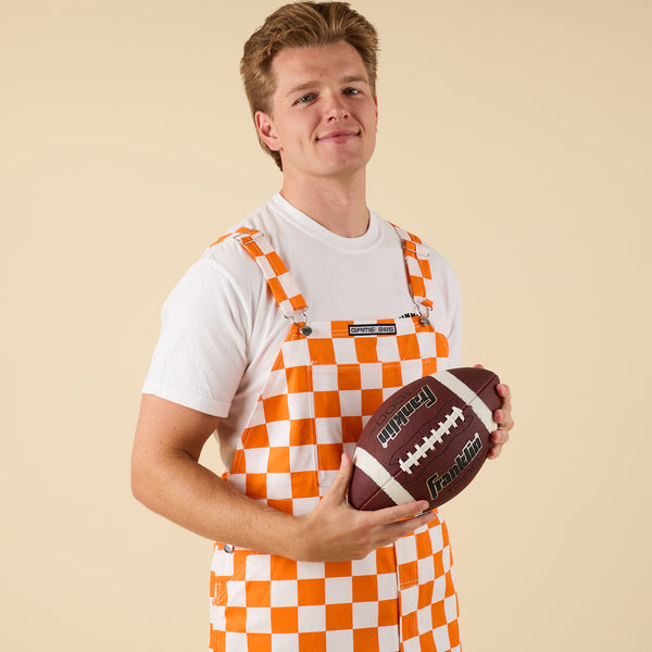Man posing for a product photo in Orange and white checkered overalls.
