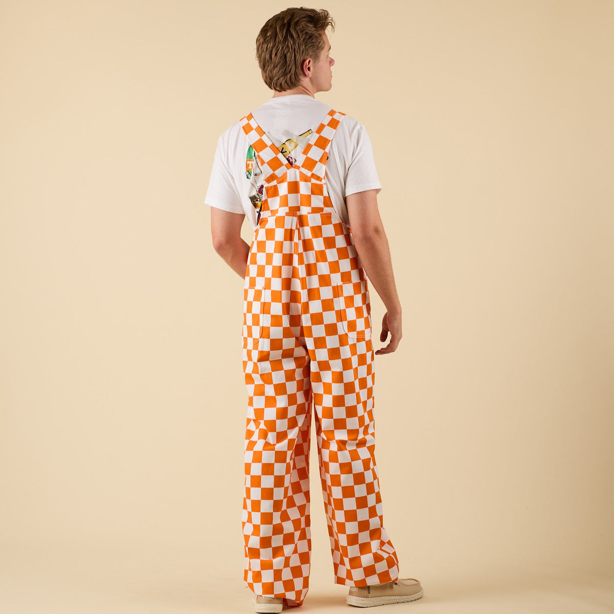 Man posing for a product photo in Orange and white checkered overalls.