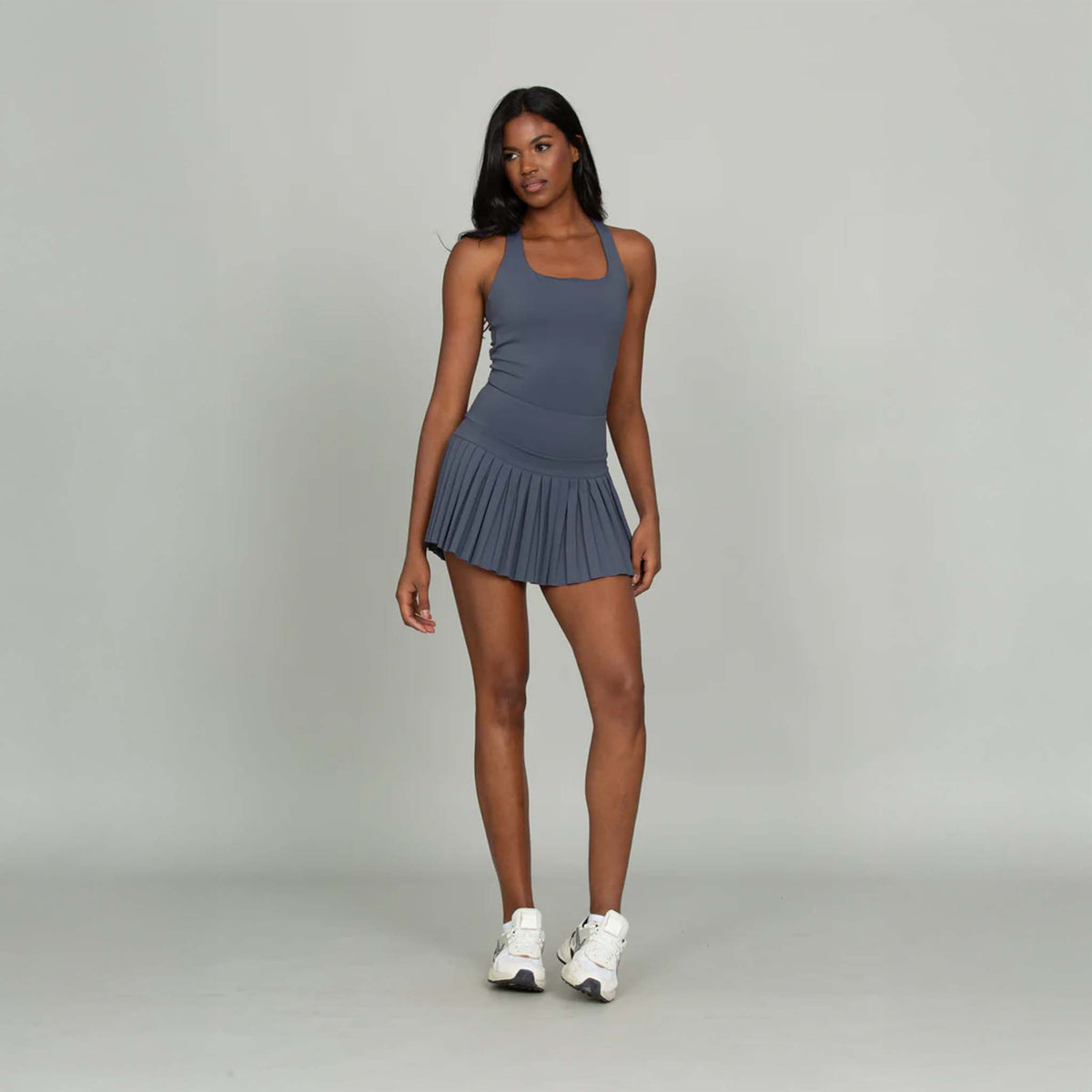 Full-body view of Gold Hinge navy strappy tennis dress styled with sneakers.