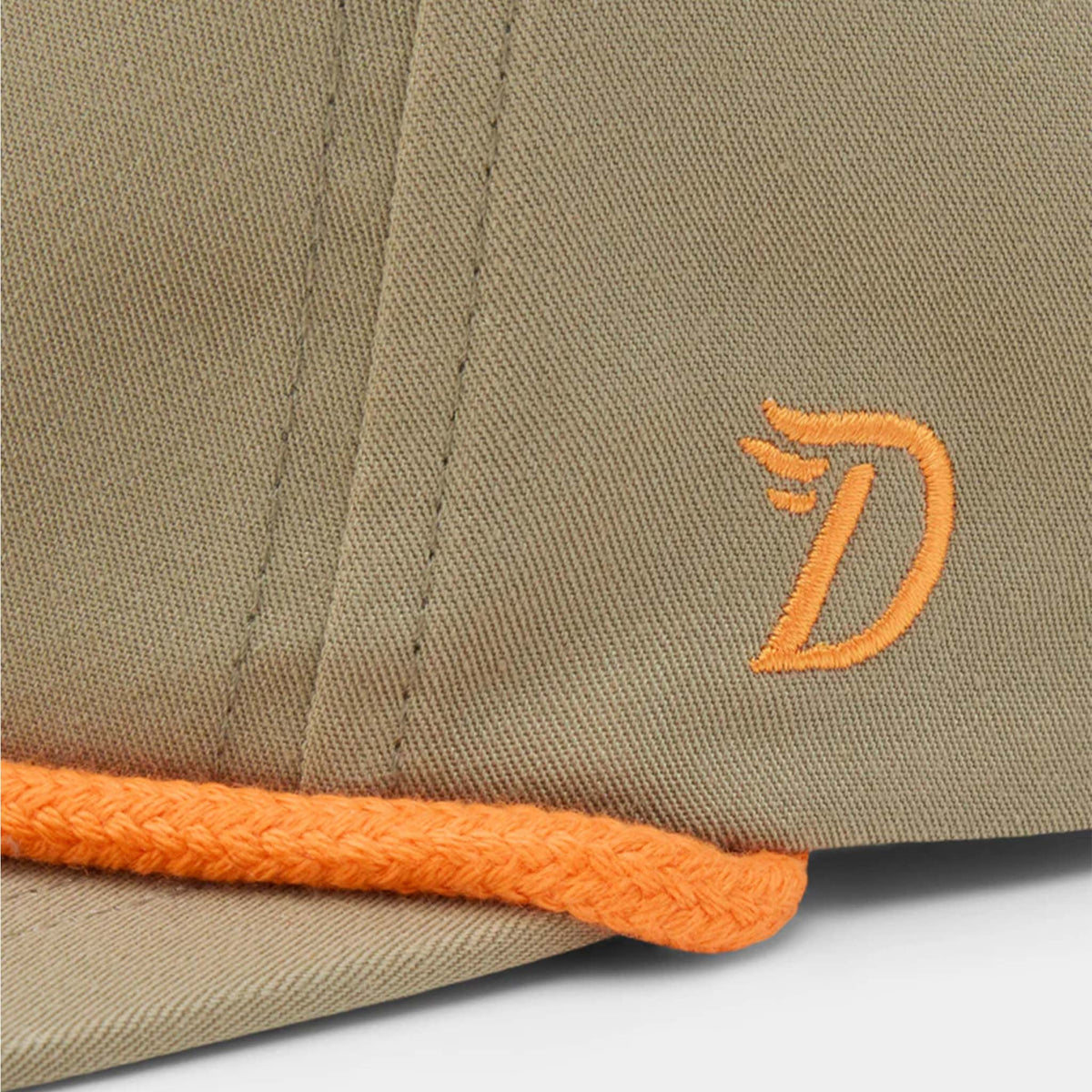 Side detail of Duck Camp sagebrush hat with orange embroidered “D” logo above orange rope trim.