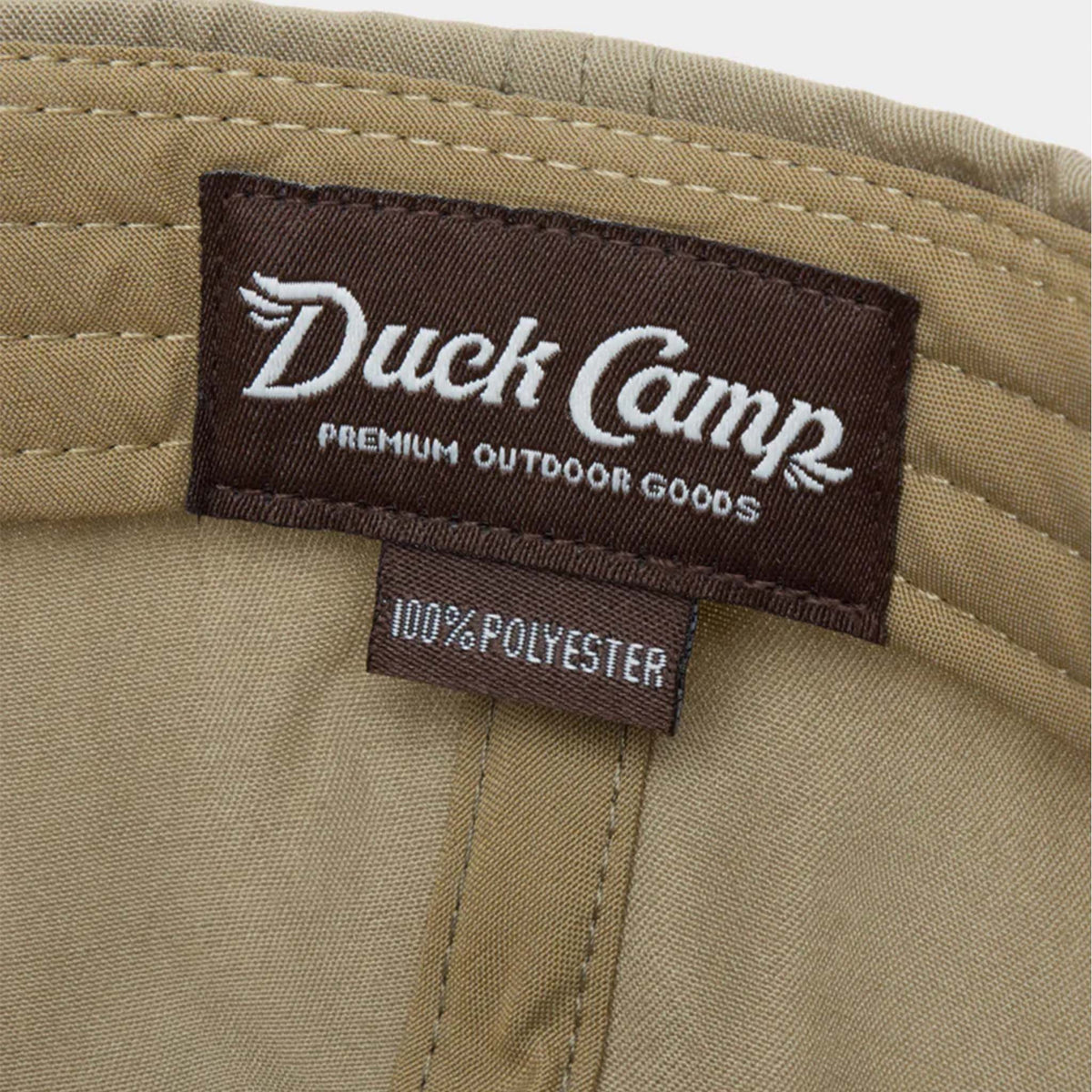 Interior label of Duck Camp sagebrush hat showing brown “Duck Camp Premium Outdoor Goods” branding and 100% polyester tag.