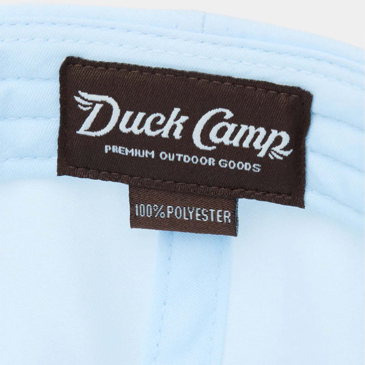 Interior view of Duck Camp Icewater blue cap with brown woven brand label and 100% polyester tag.