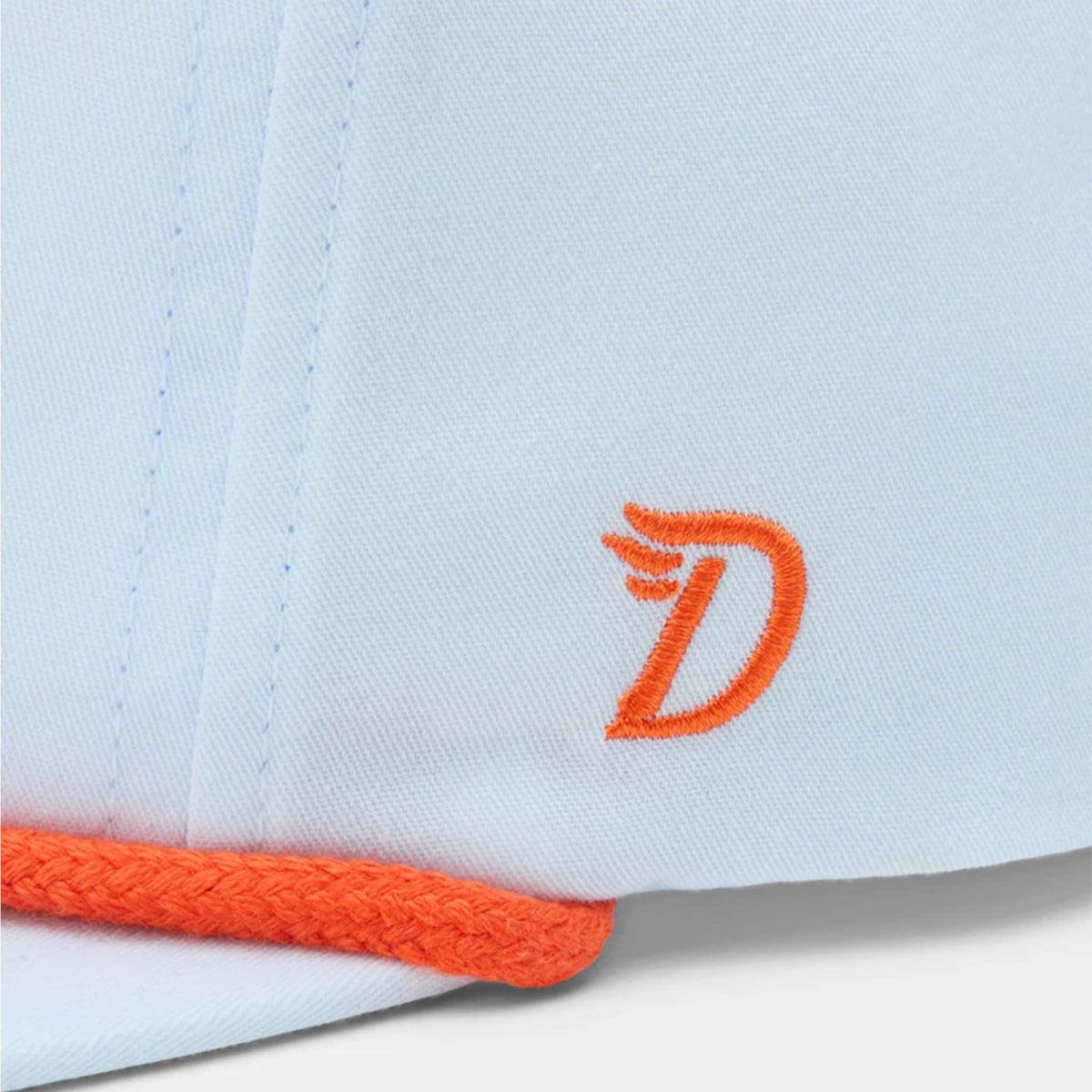 Side view of Duck Camp Icewater blue cap showing embroidered orange “D” logo above orange rope detail.
