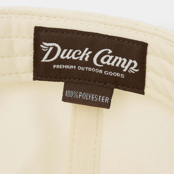 Interior label of Duck Camp hat showing brown patch with “Duck Camp Premium Outdoor Goods” and 100% polyester tag.