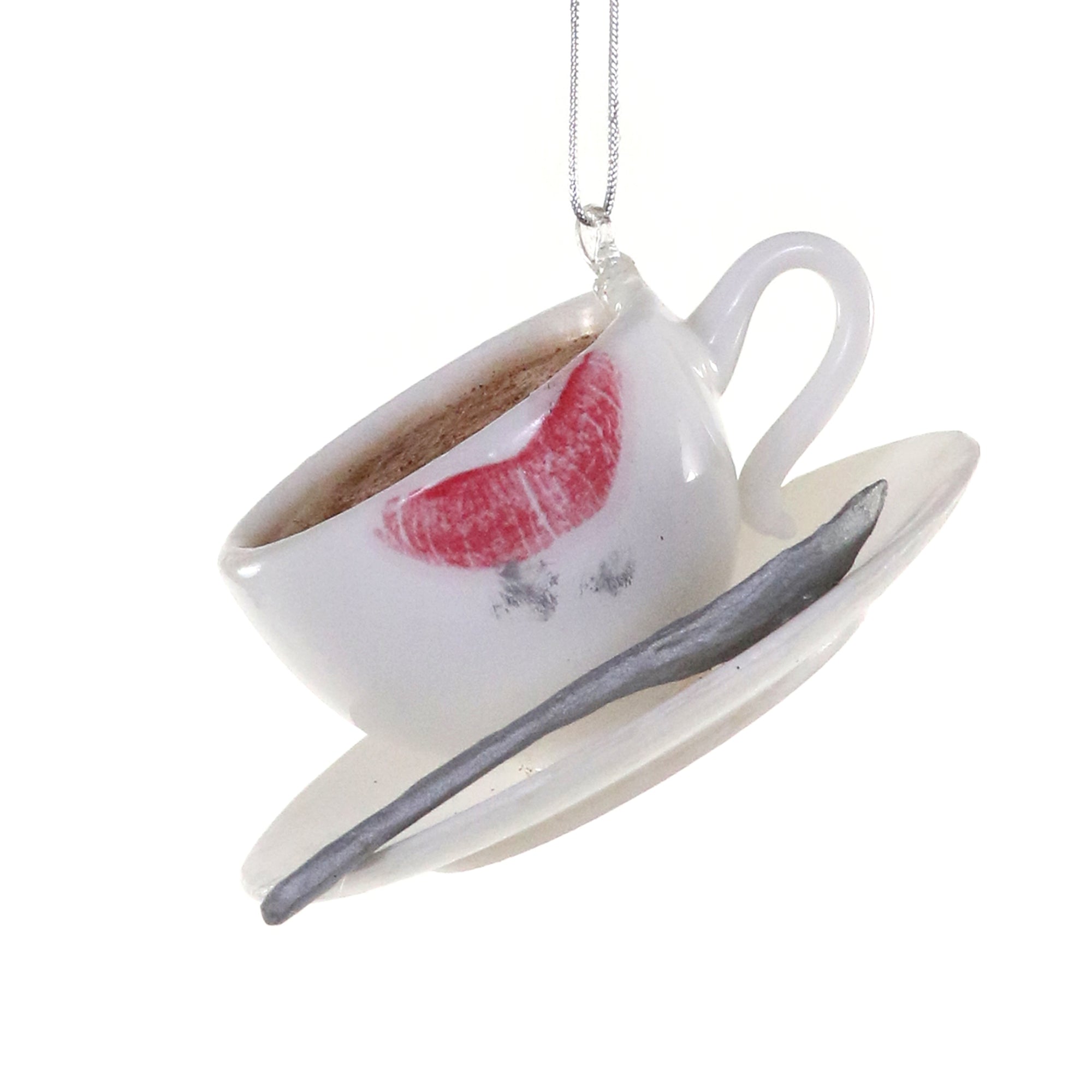 White coffee cup ornament with lipstick mark, saucer, and silver spoon.