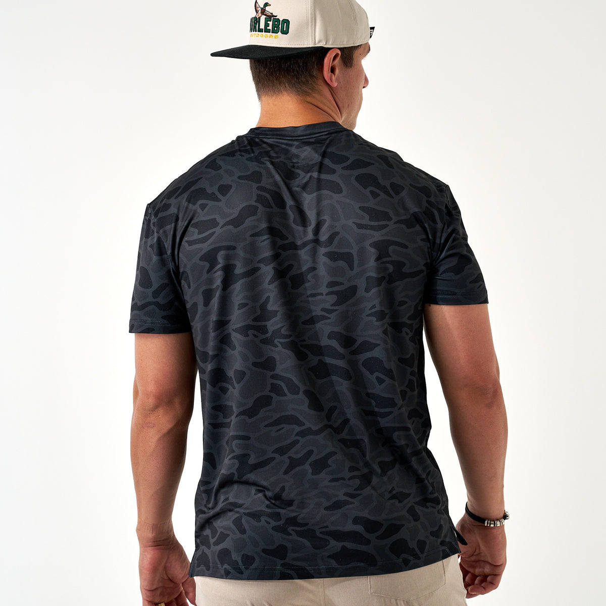 Man wearing a dark camouflage t-shirt and cap on a white background