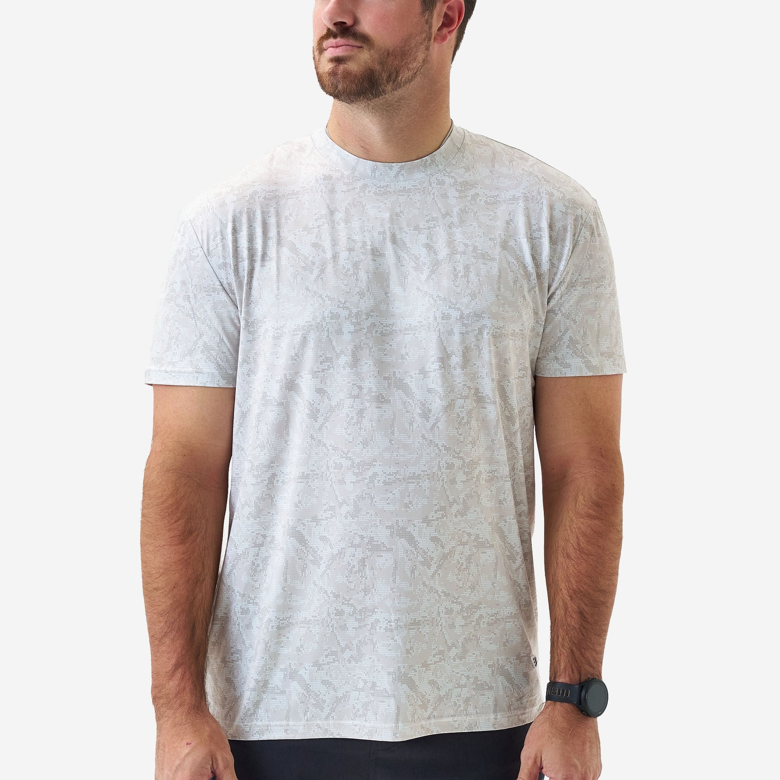 Male model wearing a light gray patterned short sleeve performance t-shirt with tonal geometric print and crew neckline, shown from the front on a white background.