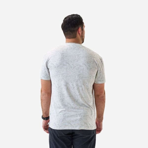 Male model wearing a light gray patterned short sleeve performance t-shirt with a subtle tonal geometric design, shown from the front on a white background.