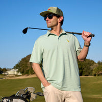 man standing on a golf course holding a golf club over his sholder.