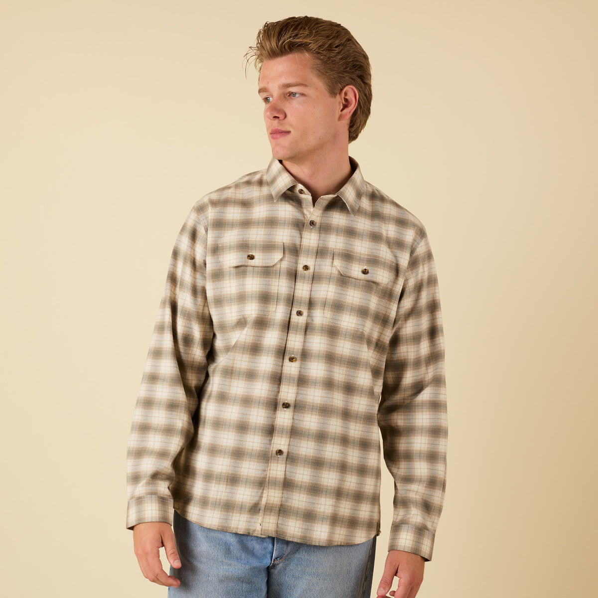 Man wearing a plaid shirt against a beige background