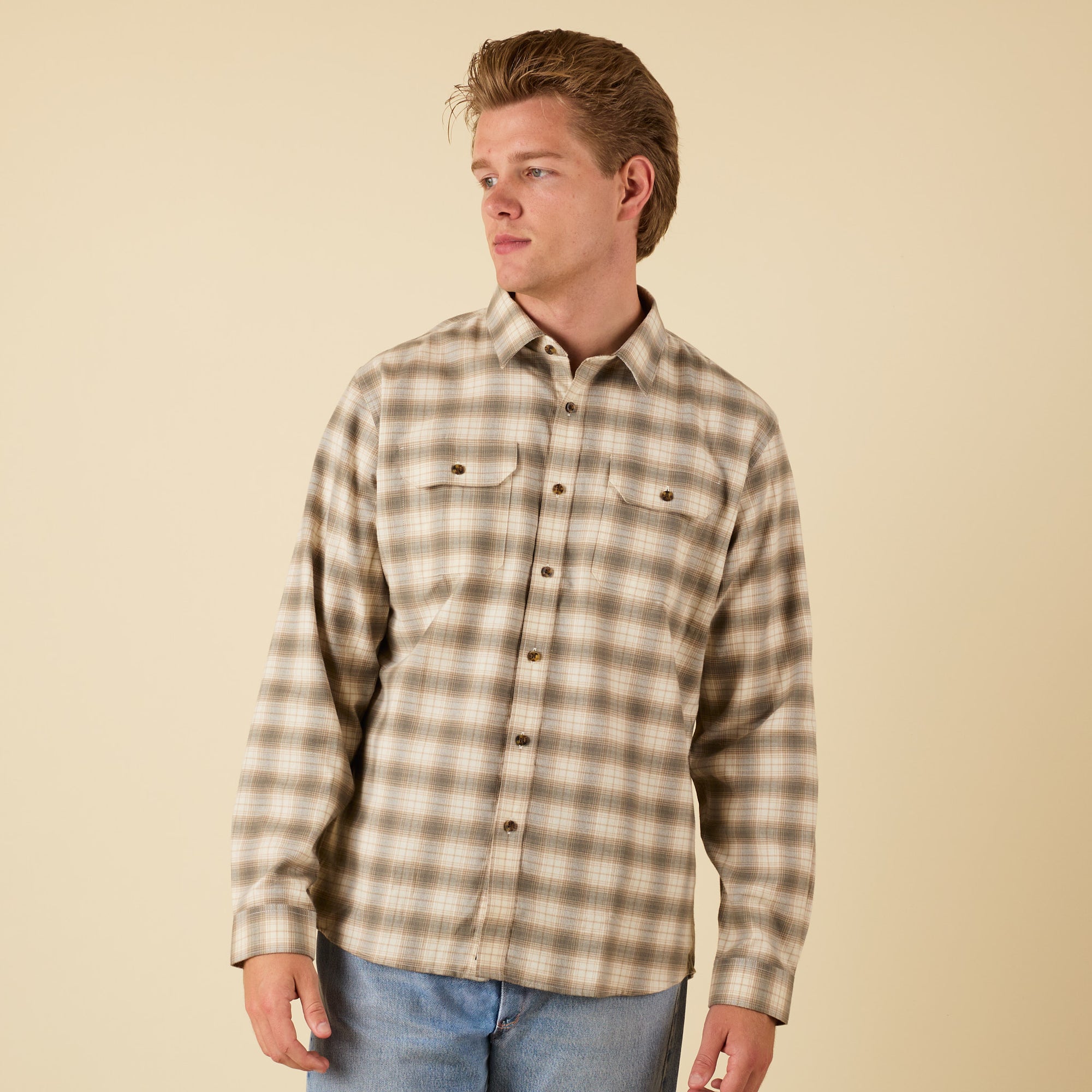 Man wearing a plaid shirt against a beige background