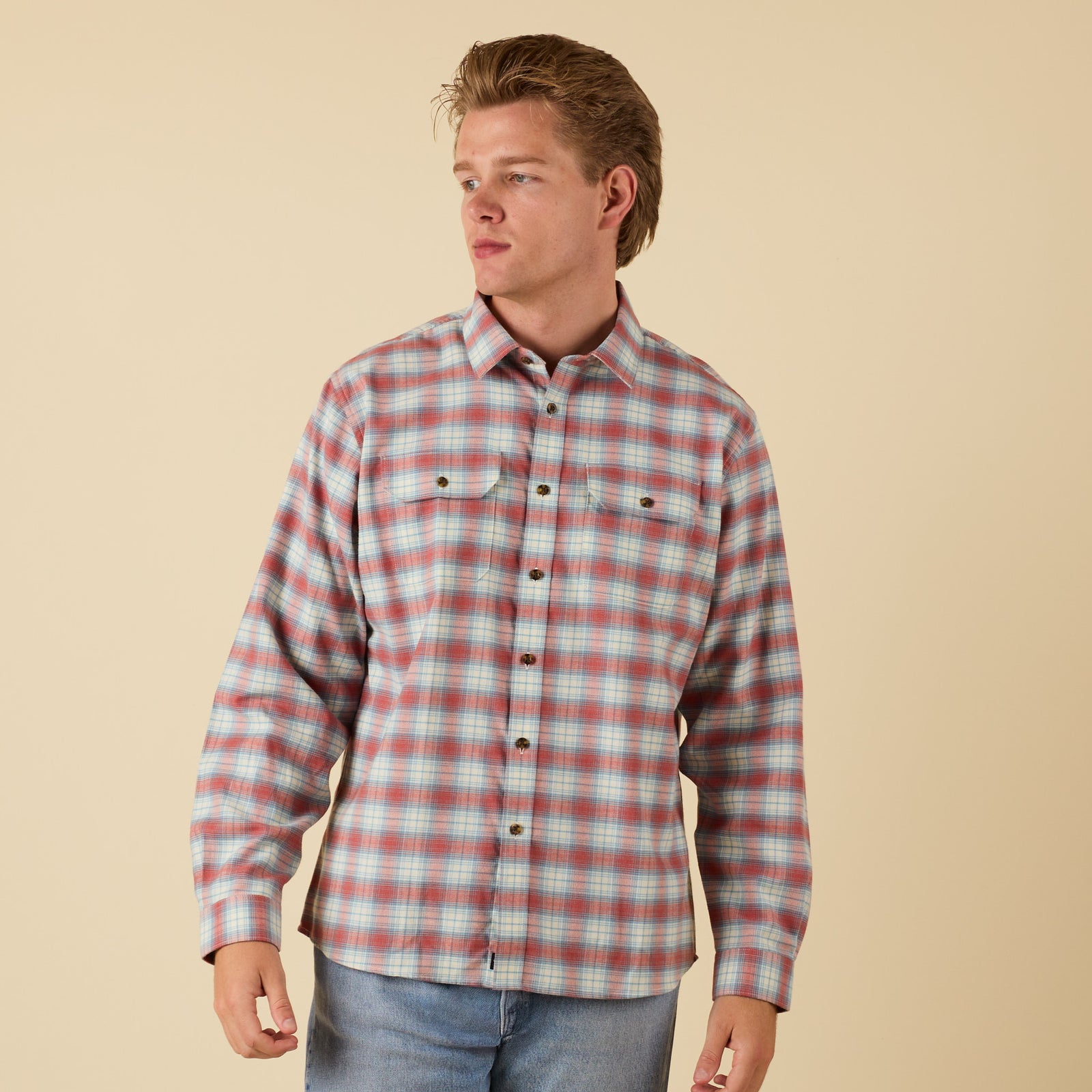Man wearing a plaid shirt against a beige background