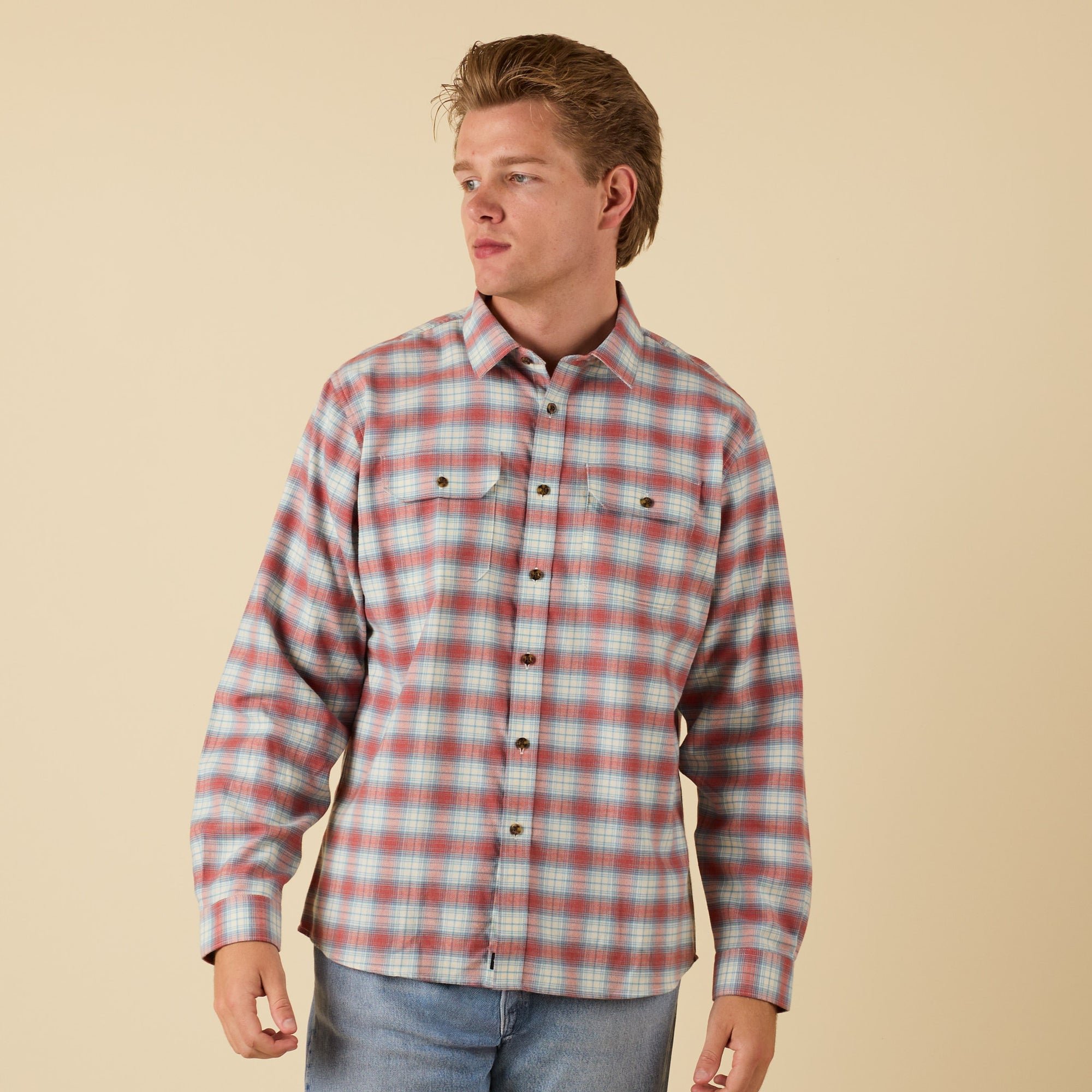 Man wearing a plaid shirt against a beige background