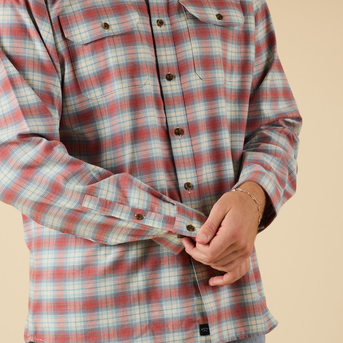 Close-up of a person wearing a red and blue plaid shirt on a beige background