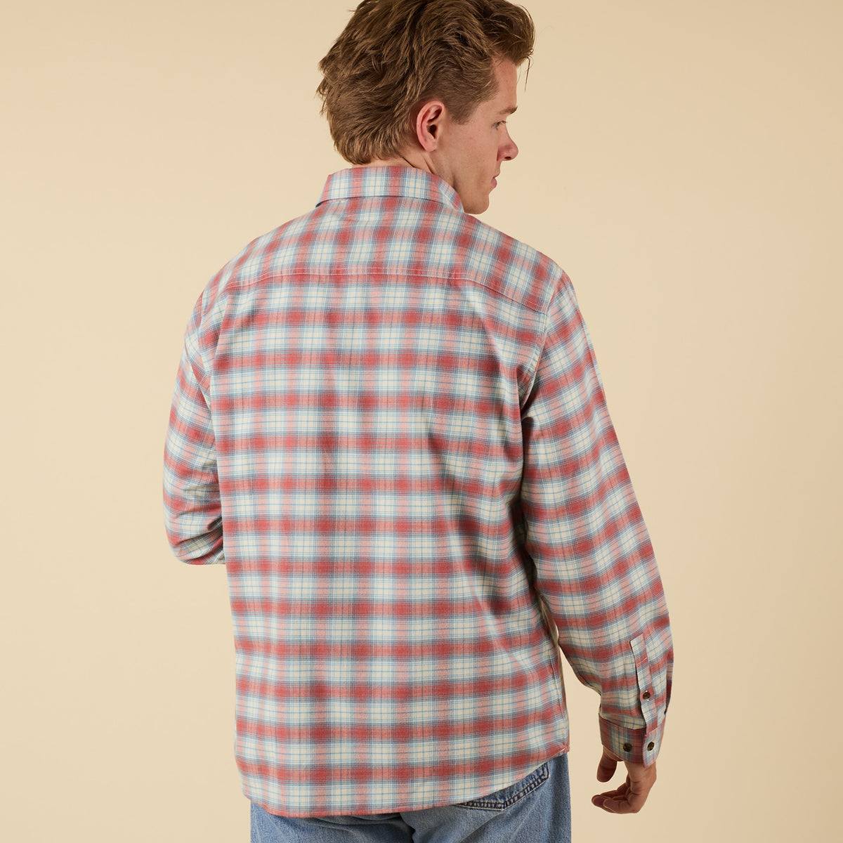 Man wearing a red and blue plaid shirt on a beige background