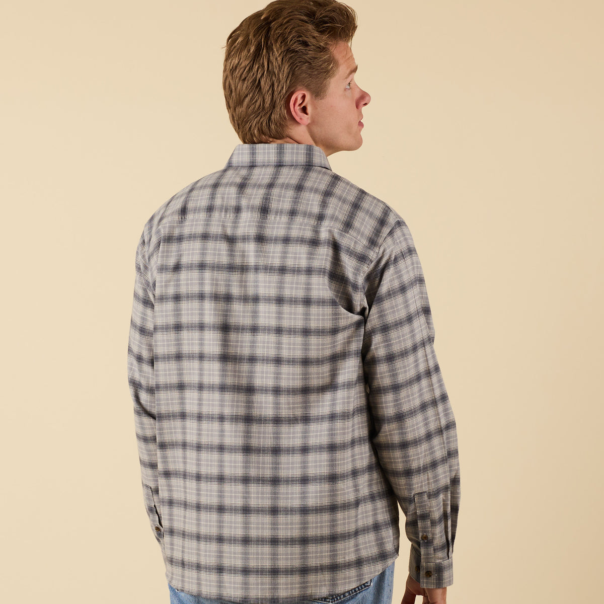 Man wearing a plaid shirt against a beige background