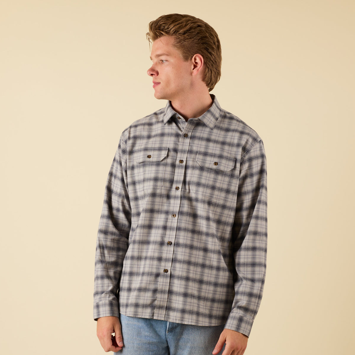 Person wearing a plaid shirt against a beige background