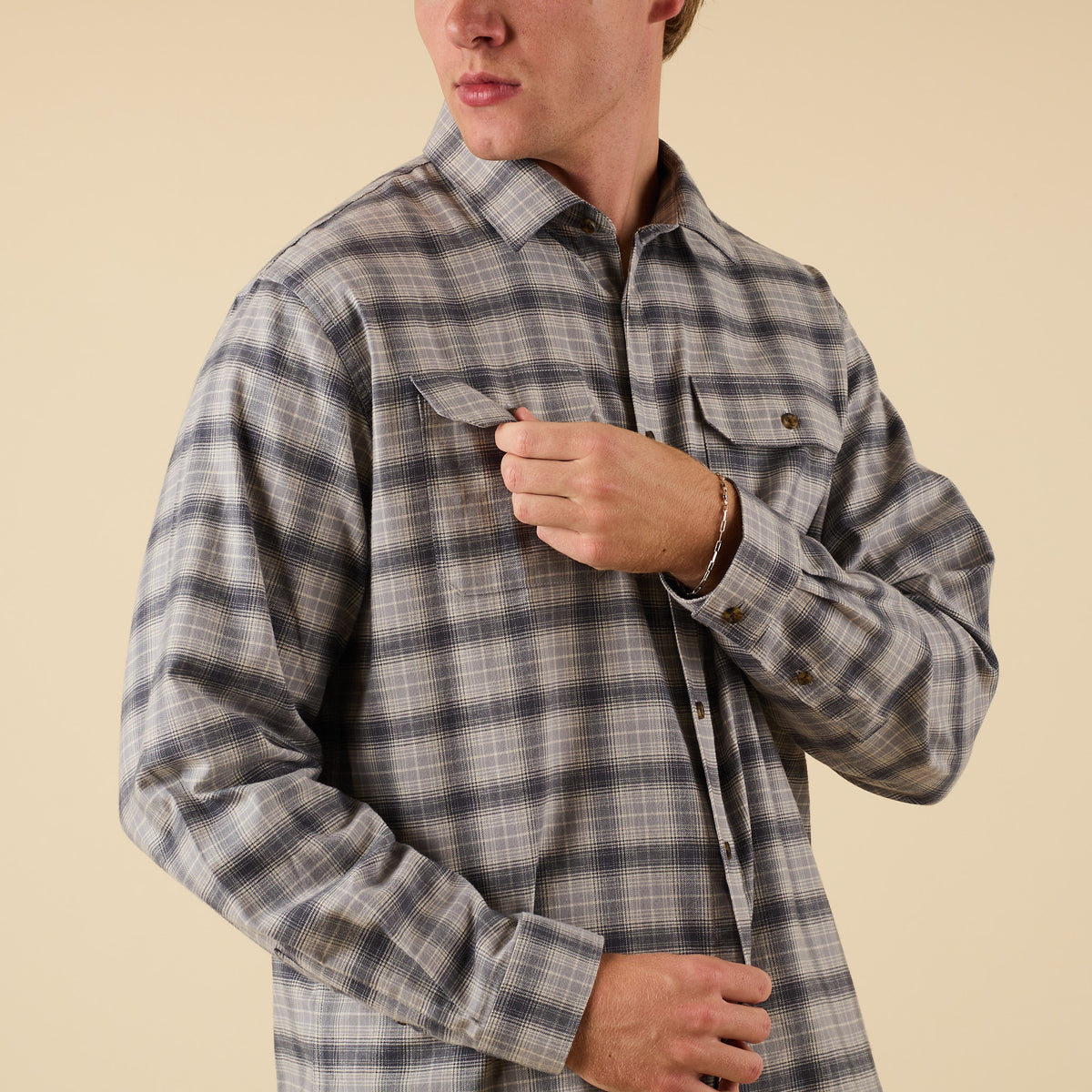 Person wearing a plaid shirt against a beige background