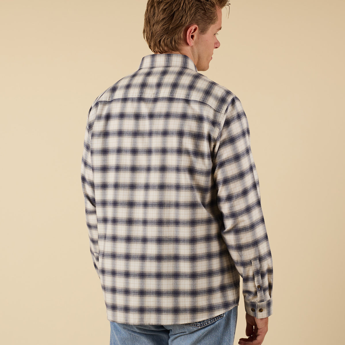 Man wearing a plaid shirt against a beige background