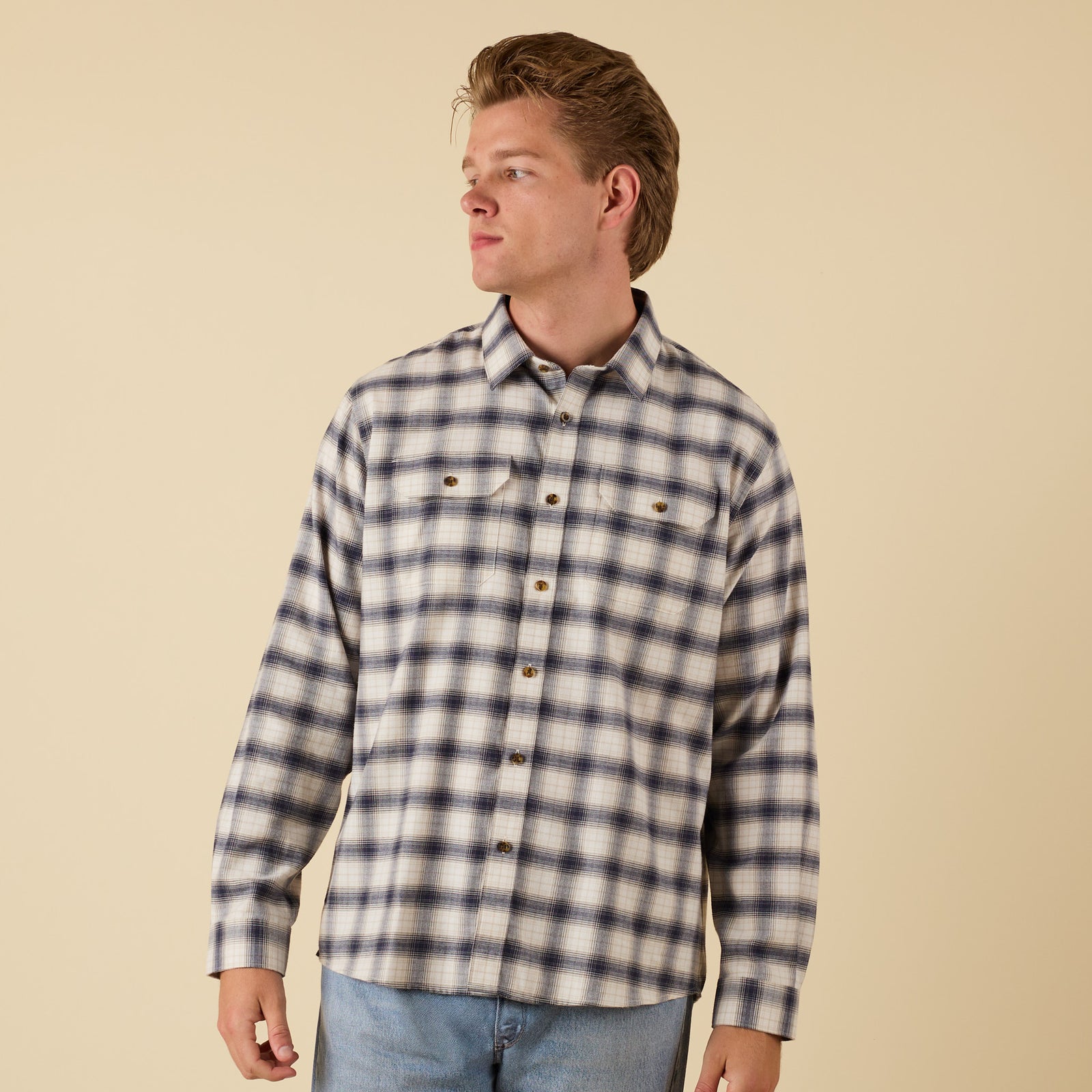 Man wearing a plaid shirt against a beige background