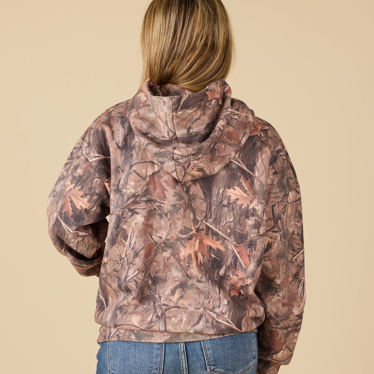 Person wearing a camouflage jacket on a beige background