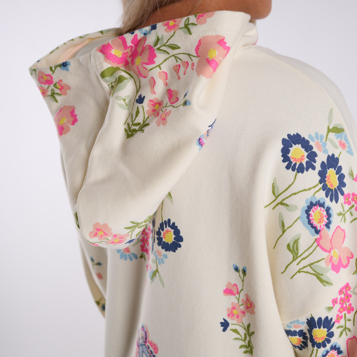 Woman wearing a cream-colored hoodie with floral print on a white background