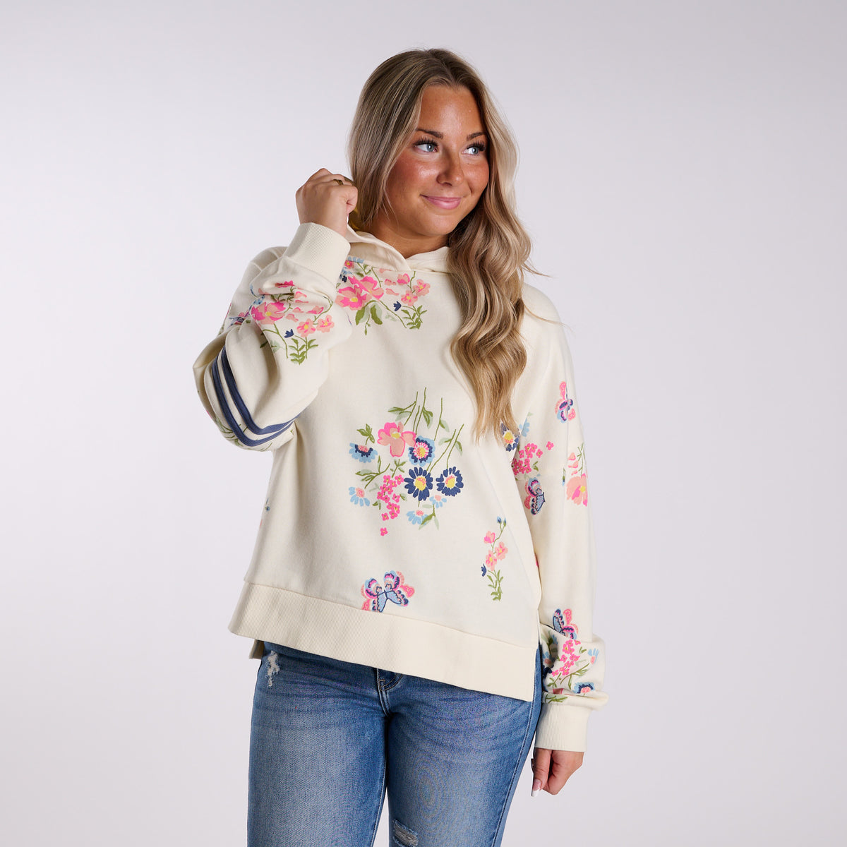 Woman wearing a cream-colored hoodie with floral print on a white background