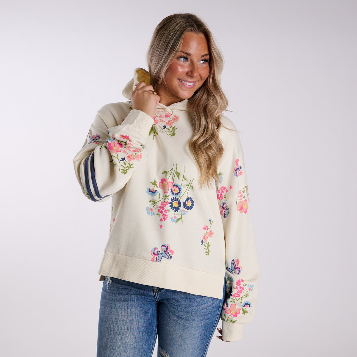 Woman wearing a cream-colored hoodie with floral print on a white background