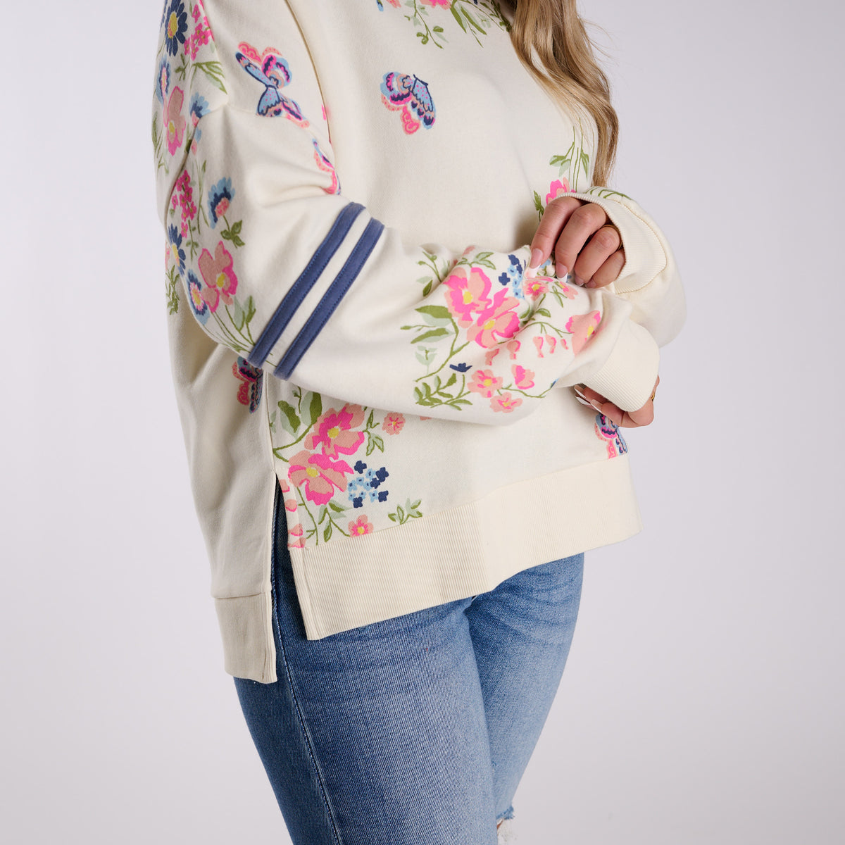 Woman wearing a cream-colored hoodie with floral print on a white background