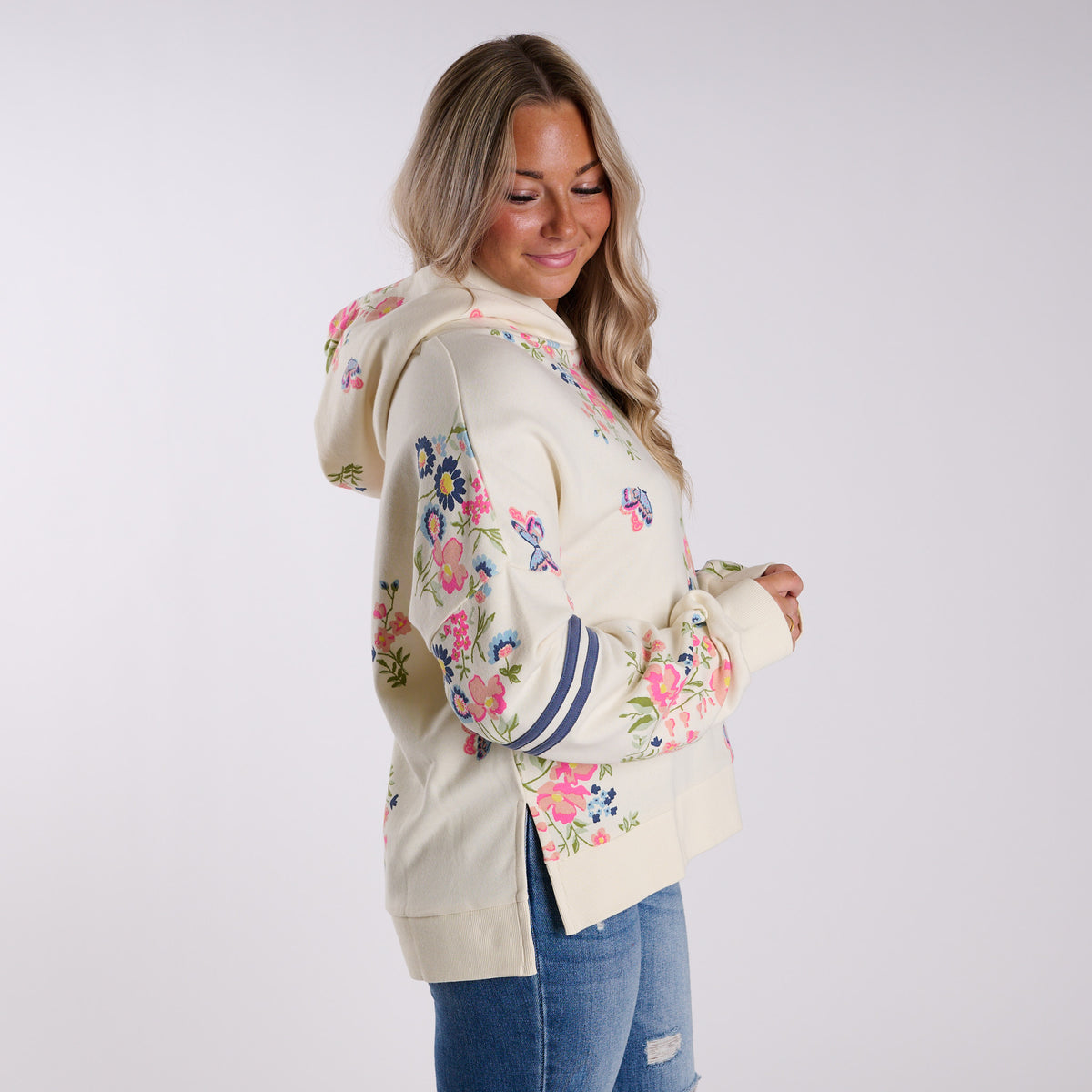 Woman wearing a cream-colored hoodie with floral print on a white background