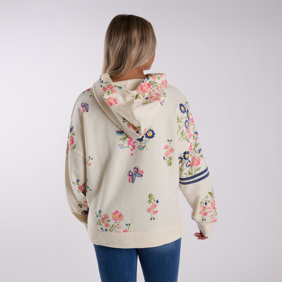 Woman wearing a cream-colored hoodie with floral print on a white background