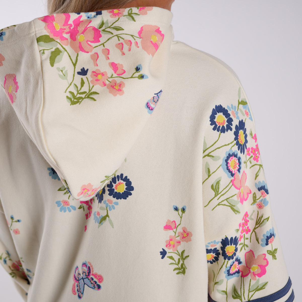 Woman wearing a cream-colored hoodie with floral print on a white background